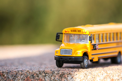 Photo of Yellow toy school bus outdoors on sunny day. Student's transport