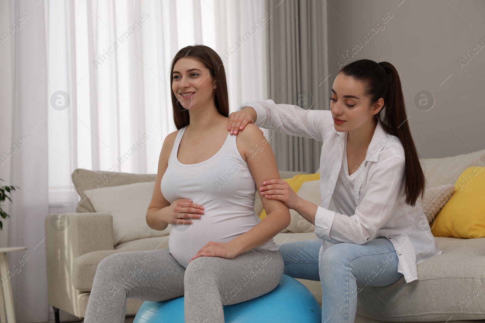 Photo of Doula working with pregnant woman in living room. Preparation for child birth