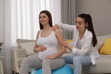 Photo of Doula working with pregnant woman in living room. Preparation for child birth