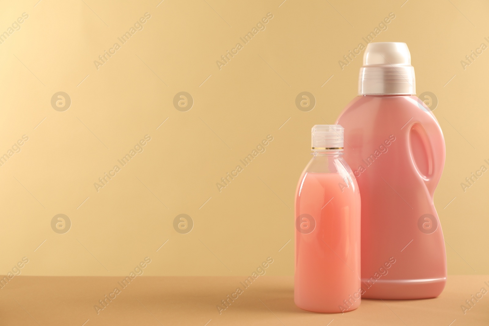 Photo of Different bottles with detergents on beige background, space for text