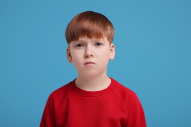 Photo of Portrait of sad little boy on light blue background