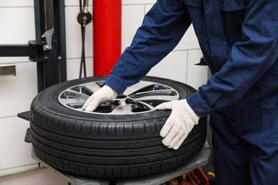 Photo of Man working with tire fitting machine at car service, closeup