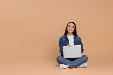 Photo of Smiling young woman with laptop on beige background, space for text