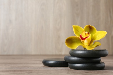 Photo of Spa stones and flower on wooden table, space for text