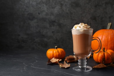 Photo of Delicious pumpkin latte on black slate table. Space for text