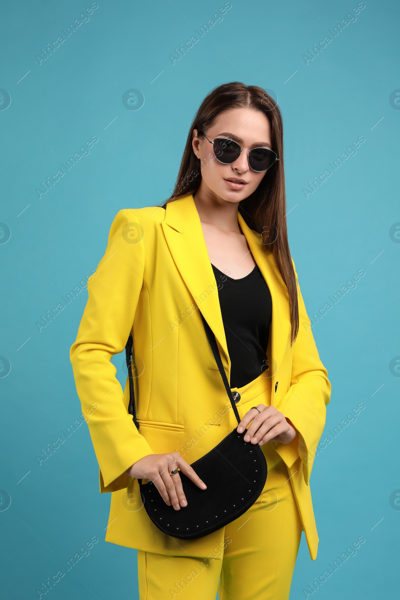 Photo of Fashionable young woman with stylish bag on light blue background