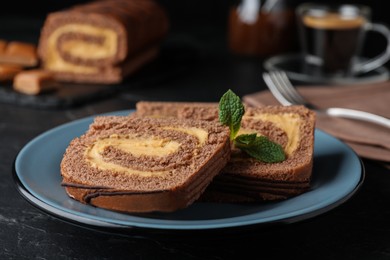 Tasty chocolate cake roll with cream on black table, closeup