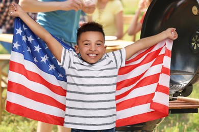 Image of 4th of July - Independence day of America. Family having picnic in park. Happy little boy with national flag of United States