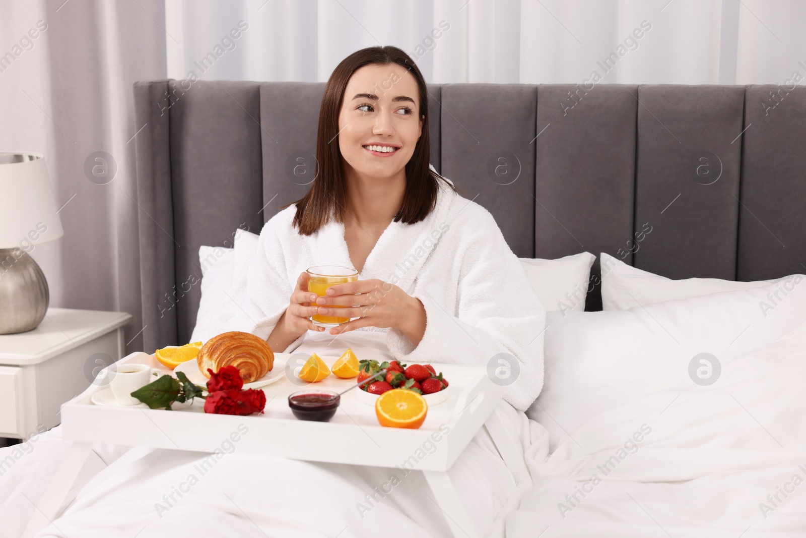 Photo of Smiling woman having breakfast in bed at home