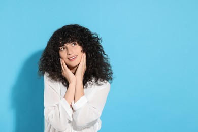 Portrait of beautiful young woman on light blue background, space for text