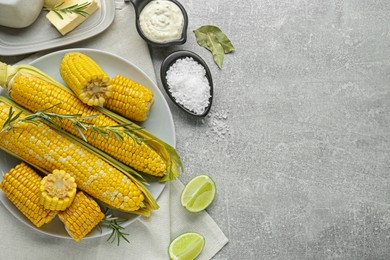 Photo of Flat lay composition with tasty boiled corn on light grey table. Space for text