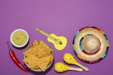 Photo of Mexican sombrero hat, nachos chips, guacamole, maracas, chili pepper and paper guitar on purple background, flat lay