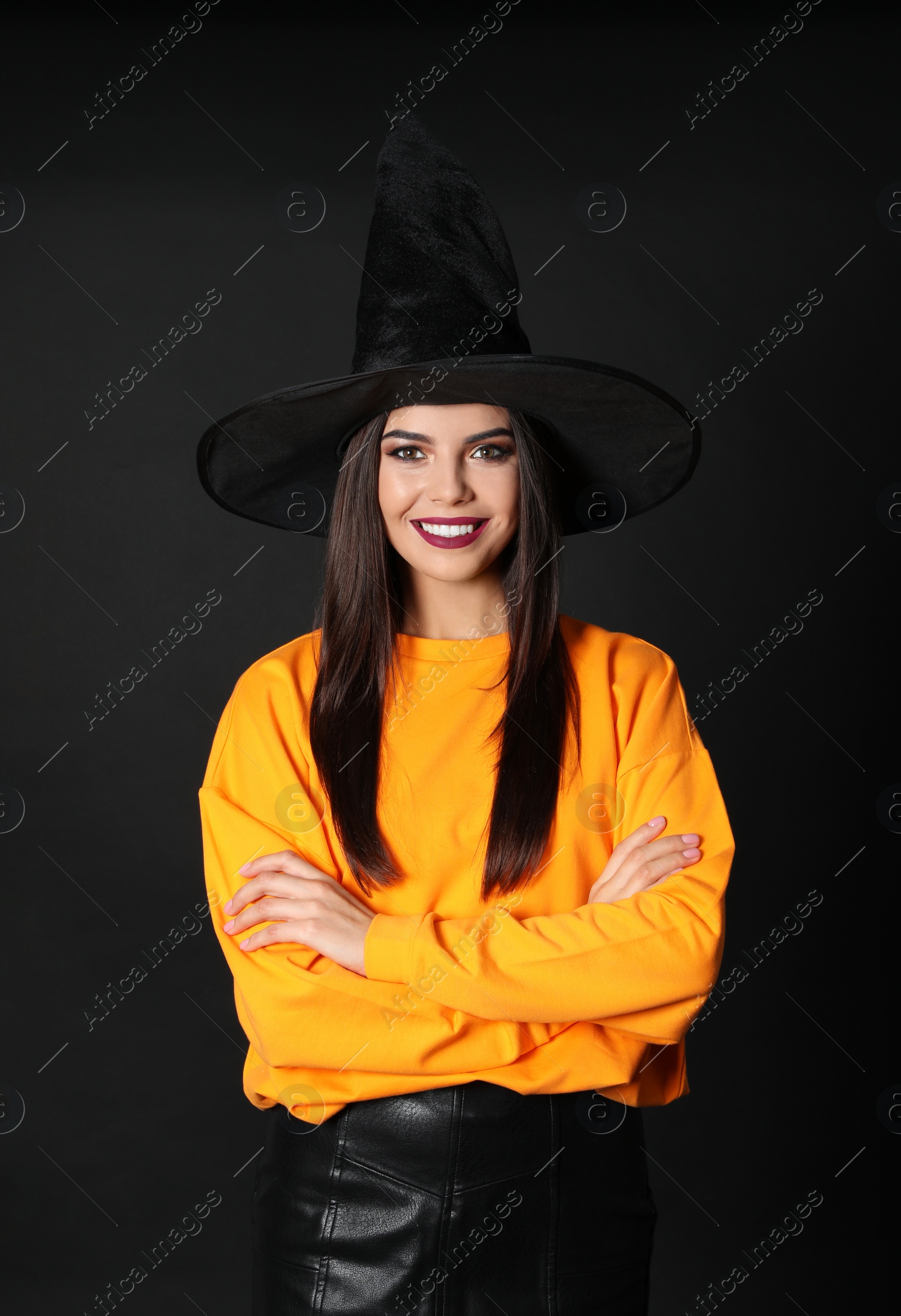 Photo of Beautiful woman wearing witch costume for Halloween party on black background