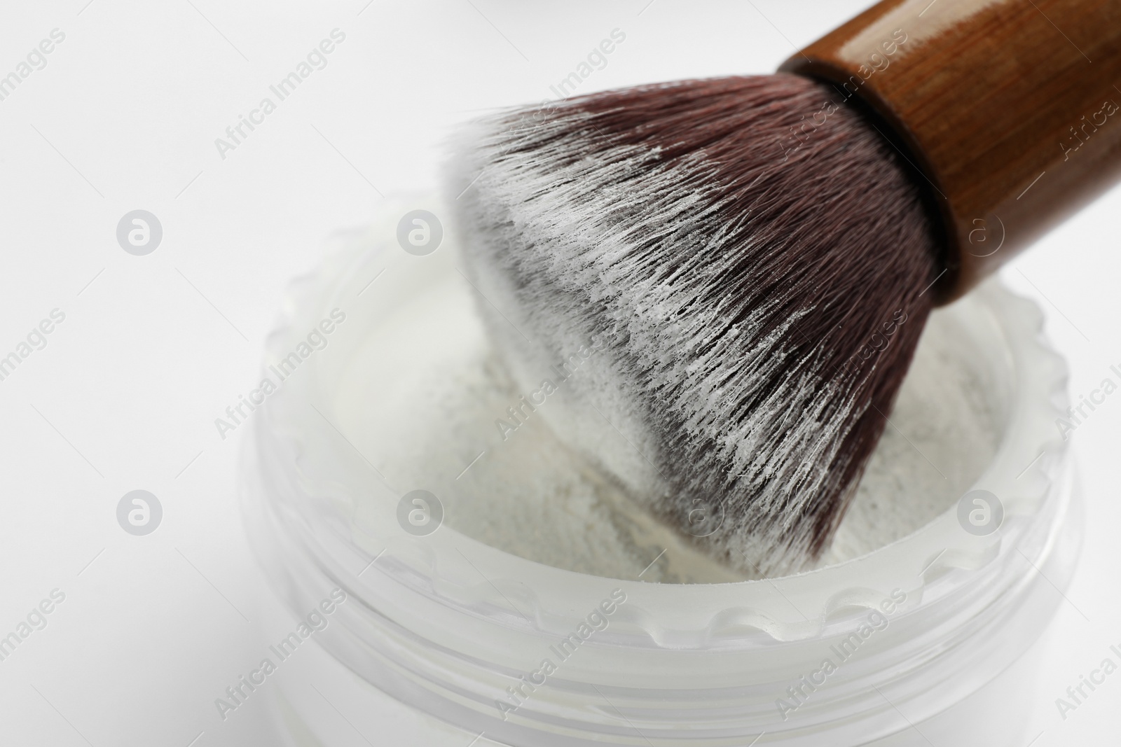 Photo of Brush with rice face powder on white background, closeup. Natural cosmetic