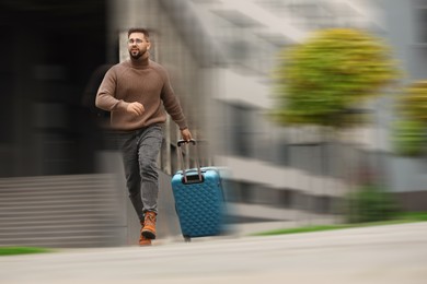 Image of Being late. Man with suitcase running on city street. Motion blur effect