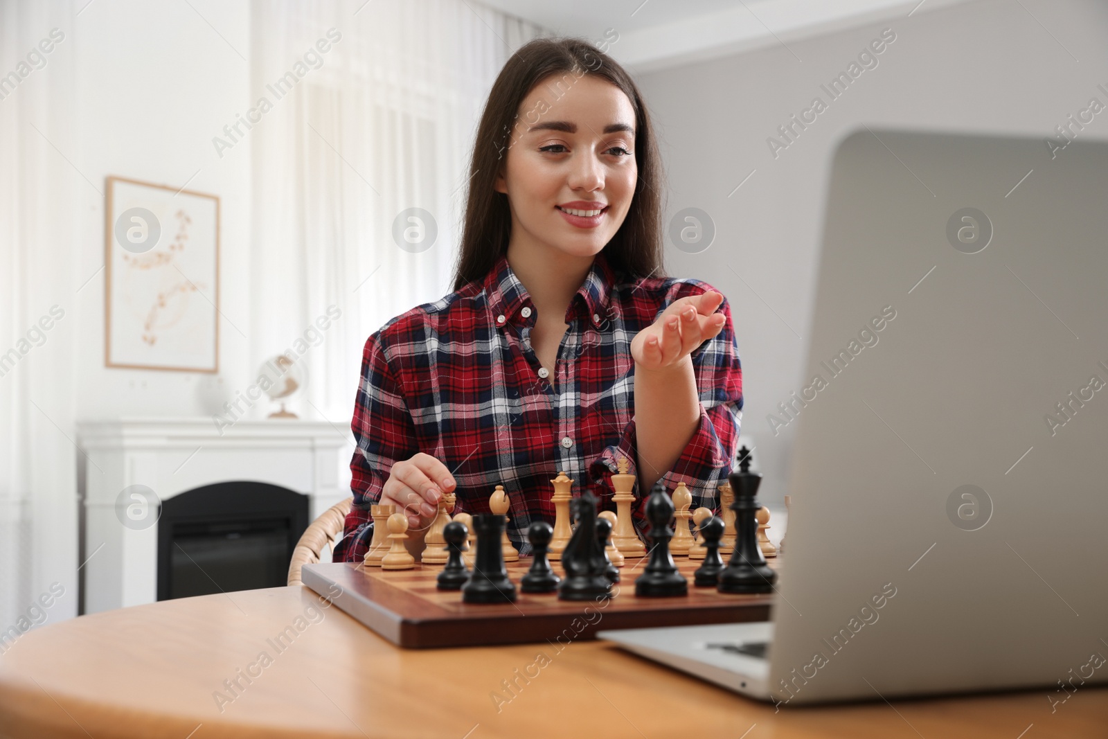 Photo of Young woman playing chess with partner through online video chat at home