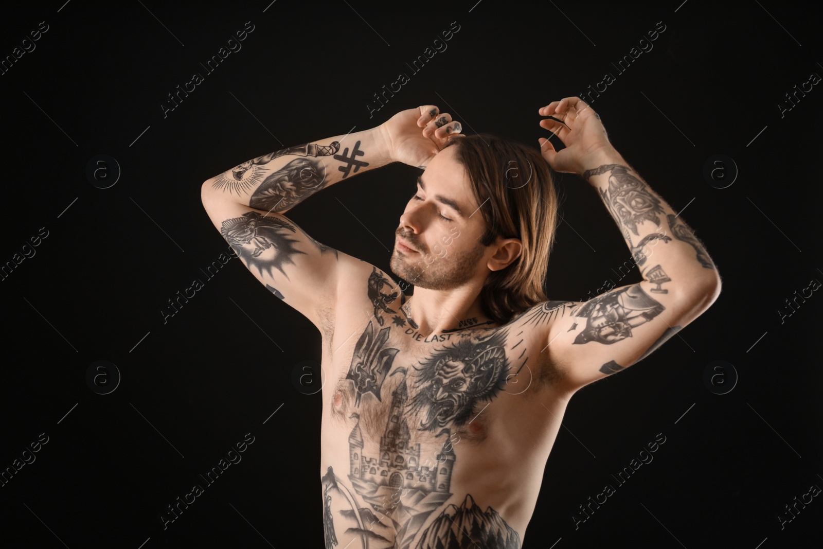 Photo of Young man with tattoos on body against black background