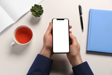 Photo of Man with smartphone at white table, top view