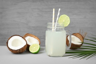 Photo of Mason jar with coconut water and fresh nuts on grey table