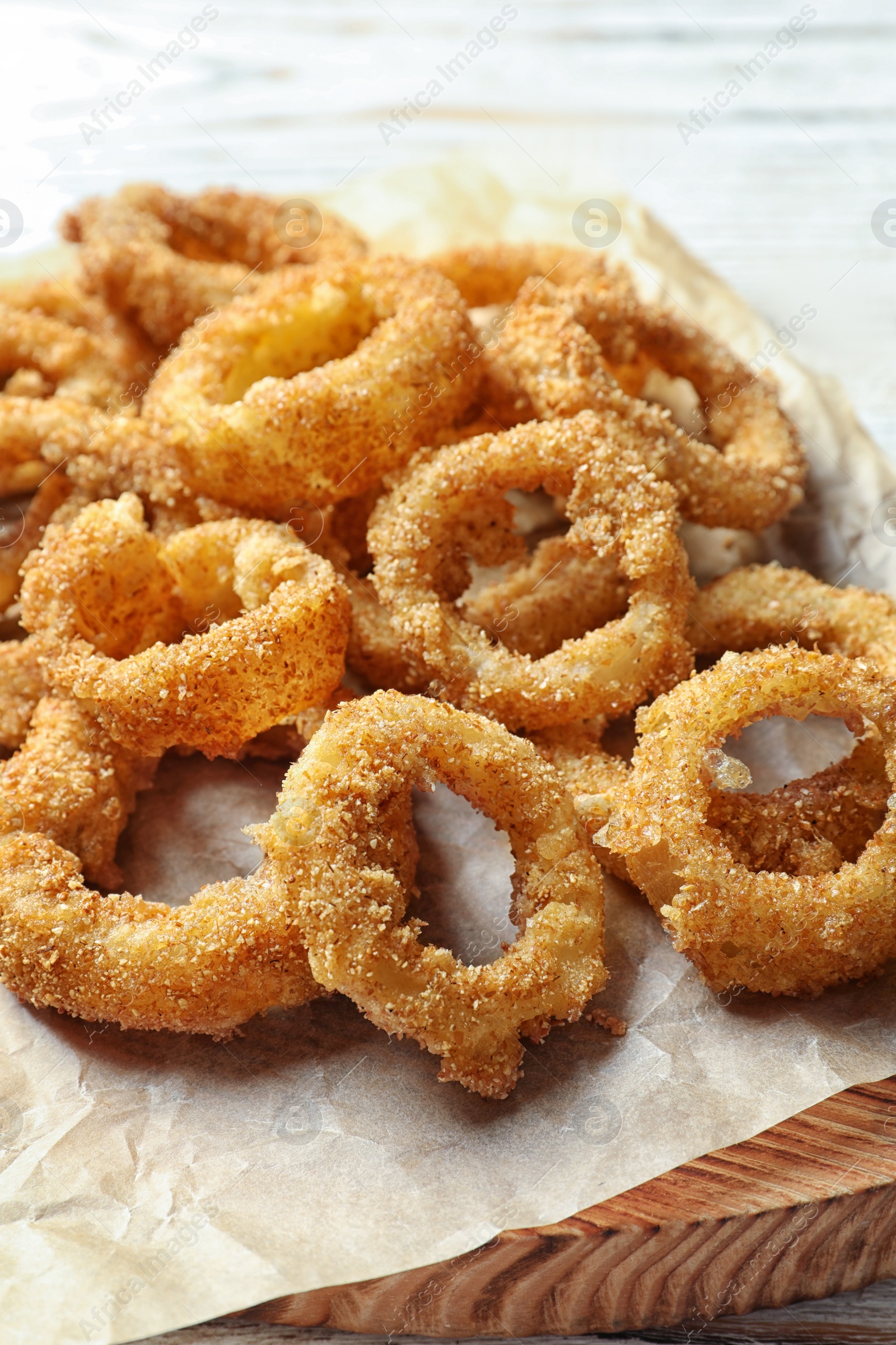 Photo of Homemade crunchy fried onion rings on wooden board, closeup