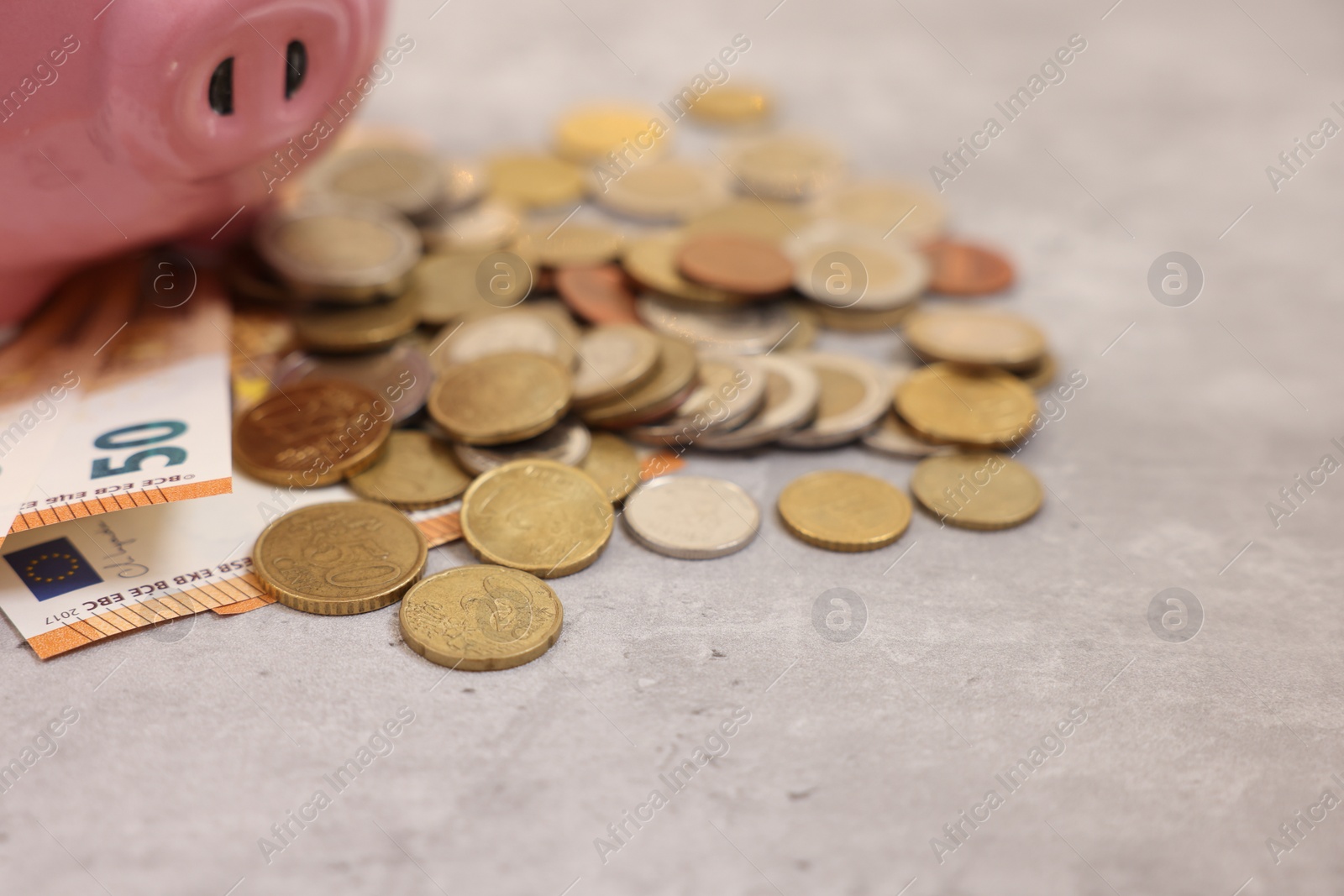 Piggy bank with euro banknotes and coins on grey table, closeup. Space for text Photo of Piggy bank with euro banknotes and coins on grey table, closeup. Space for text