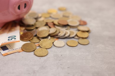 Photo of Piggy bank with euro banknotes and coins on grey table, closeup. Space for text