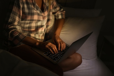 Photo of Woman using laptop in bed at night, closeup. Sleeping disorder problem