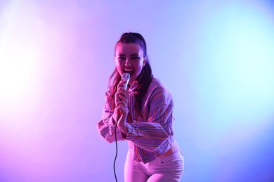 Photo of Emotional woman with microphone singing on bright background