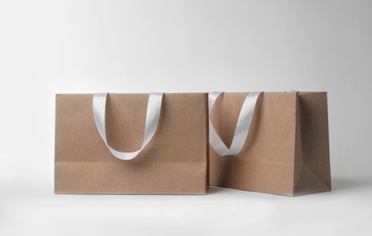 Paper shopping bags with ribbon handles on white background. Mockup for design