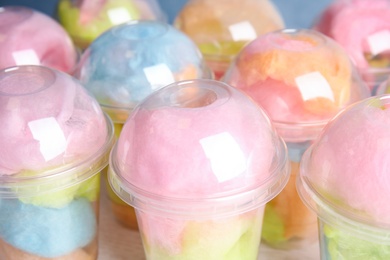 Photo of Many plastic cups with tasty cotton candies on table, closeup