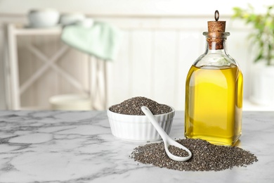 Composition with bottle of chia oil and seeds on table, space for text