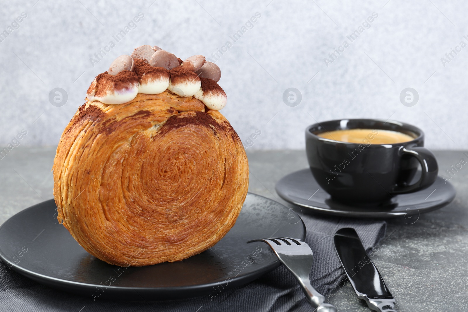 Photo of Round croissant with chocolate chips and cream served on grey table. Tasty puff pastry