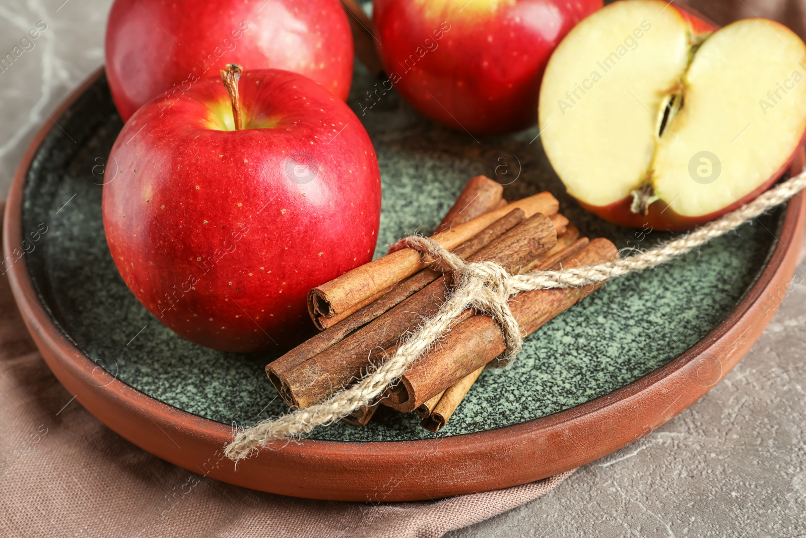 Photo of Fresh apples and cinnamon sticks on plate, closeup