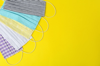 Photo of Homemade protective face masks on yellow background, flat lay. Space for text