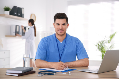 Portrait of male doctor at table in modern clinic