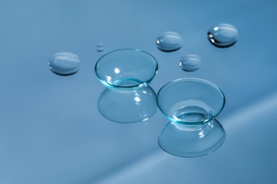 Contact lenses and drops of water on light blue reflective surface