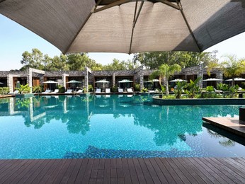 Swimming pool with wooden deck, exotic plants, umbrellas and sunbeds at luxury resort