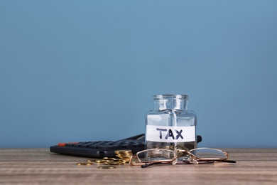 Photo of Glass jar with label "TAX" and coins on table