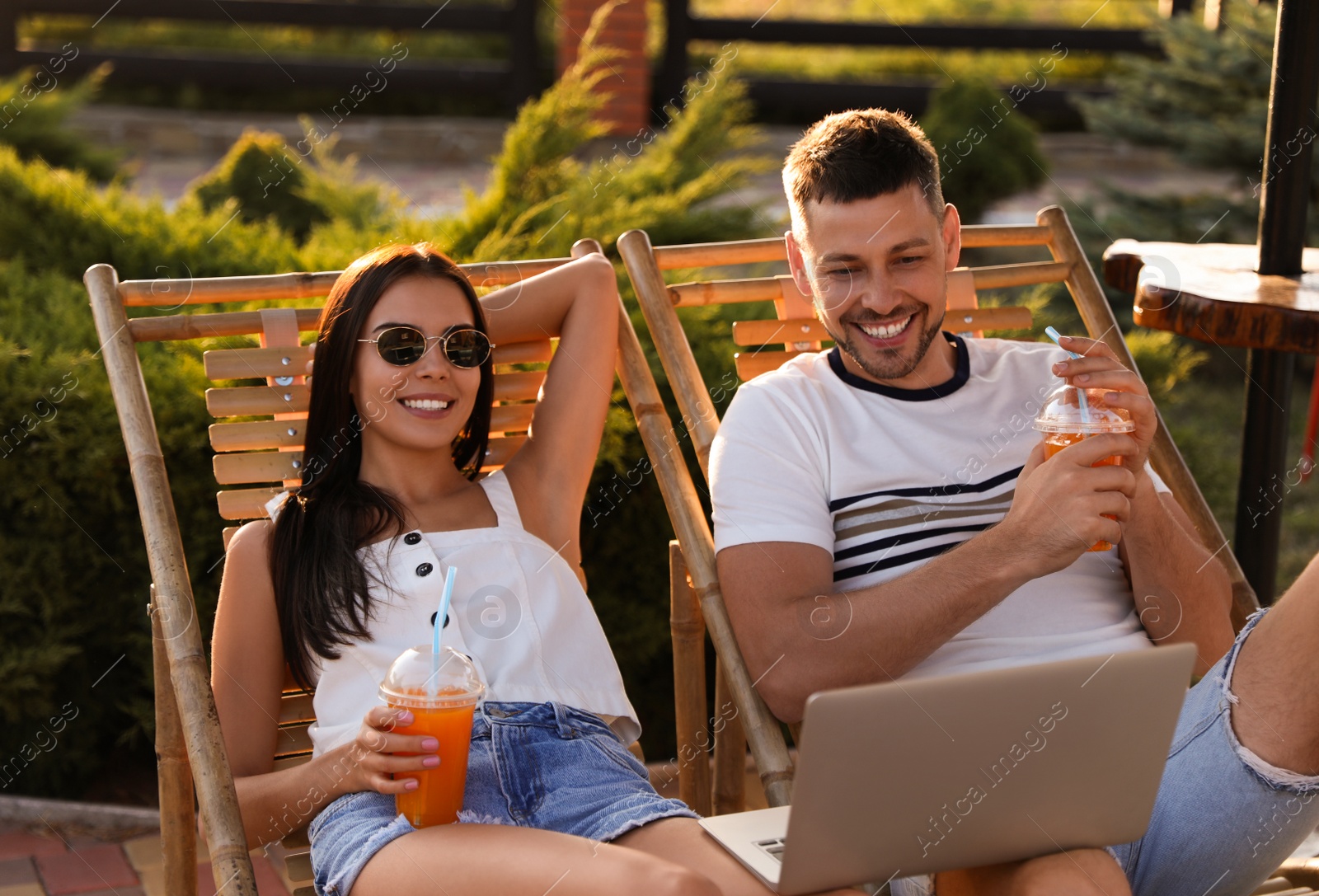 Image of Happy couple with laptop resting together outdoors