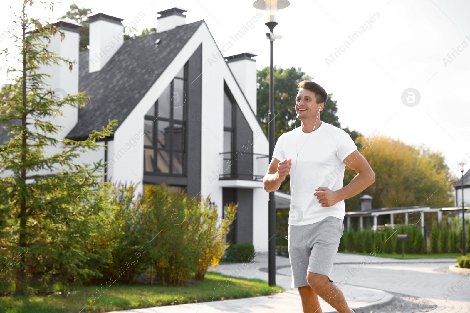Photo of Young man with earphones running outdoors on sunny morning. Healthy lifestyle