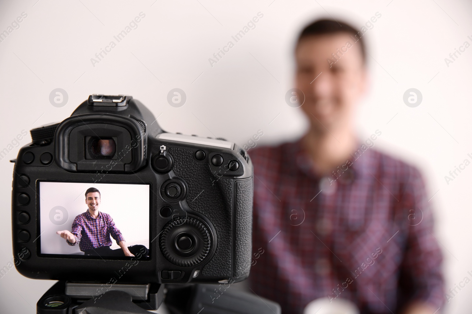 Photo of Male blogger on camera screen near light wall, closeup