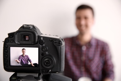 Male blogger on camera screen near light wall, closeup