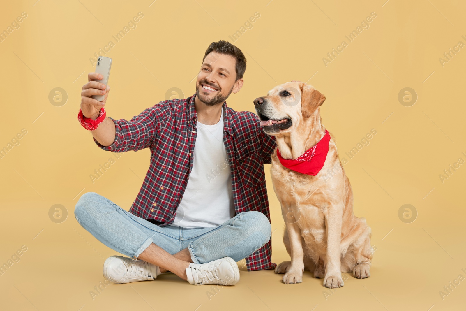 Photo of Man taking selfie with his cute Labrador Retriever on beige background
