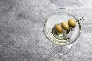 Martini cocktail with olives on grey table, above view. Space for text