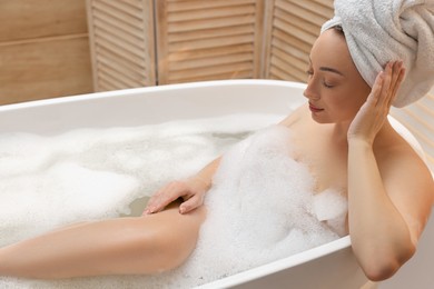 Photo of Beautiful woman taking bath with foam in tub indoors, space for text