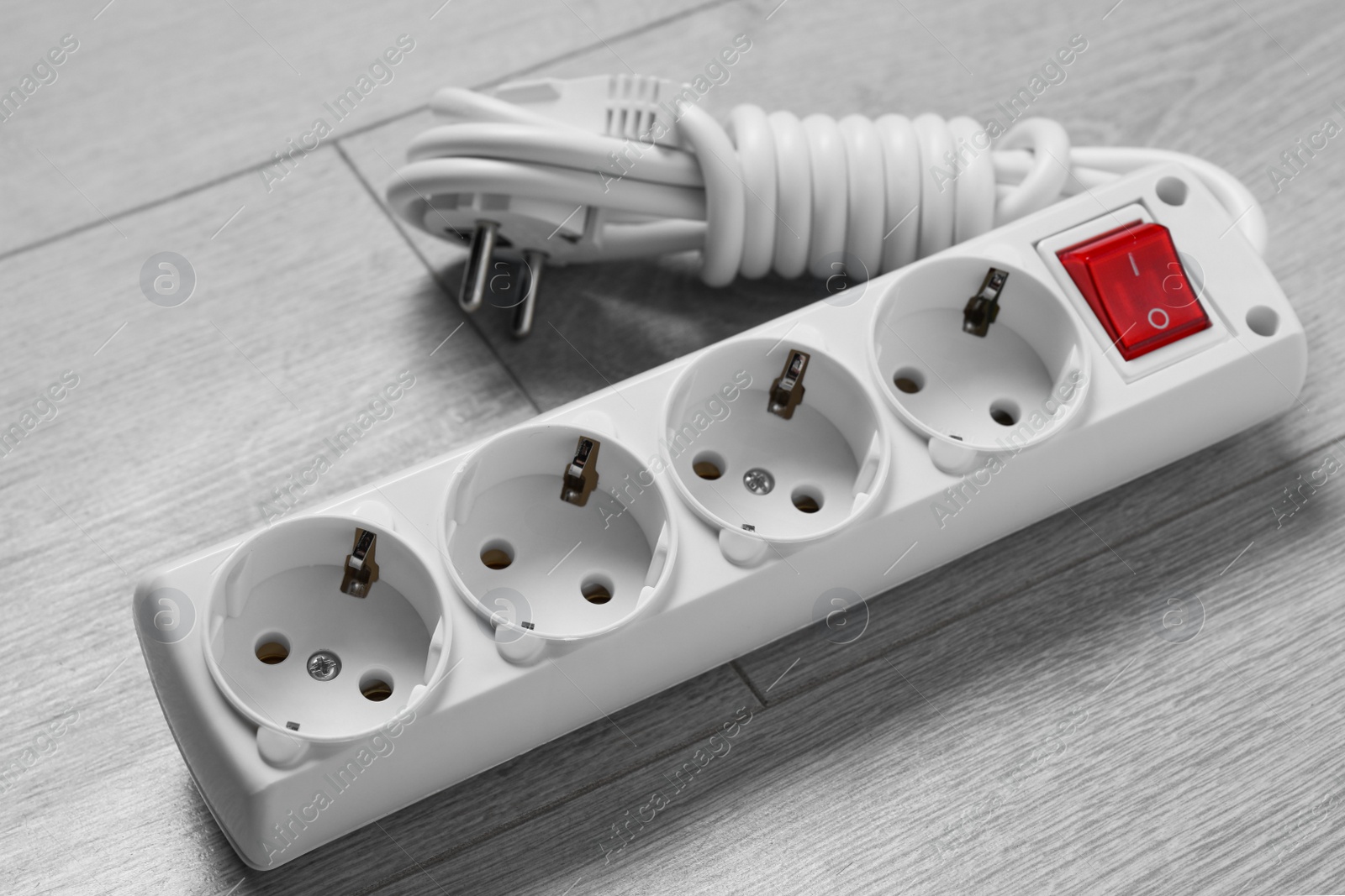 Photo of Power strip on wooden floor, closeup. Electrician's equipment