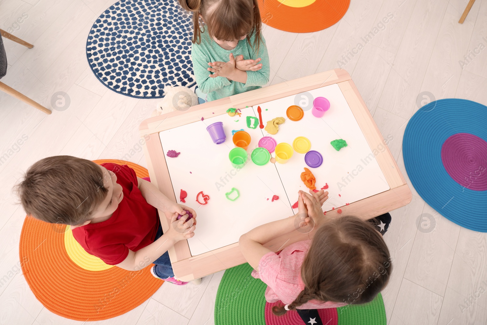 Photo of Cute little children using play dough at table indoors