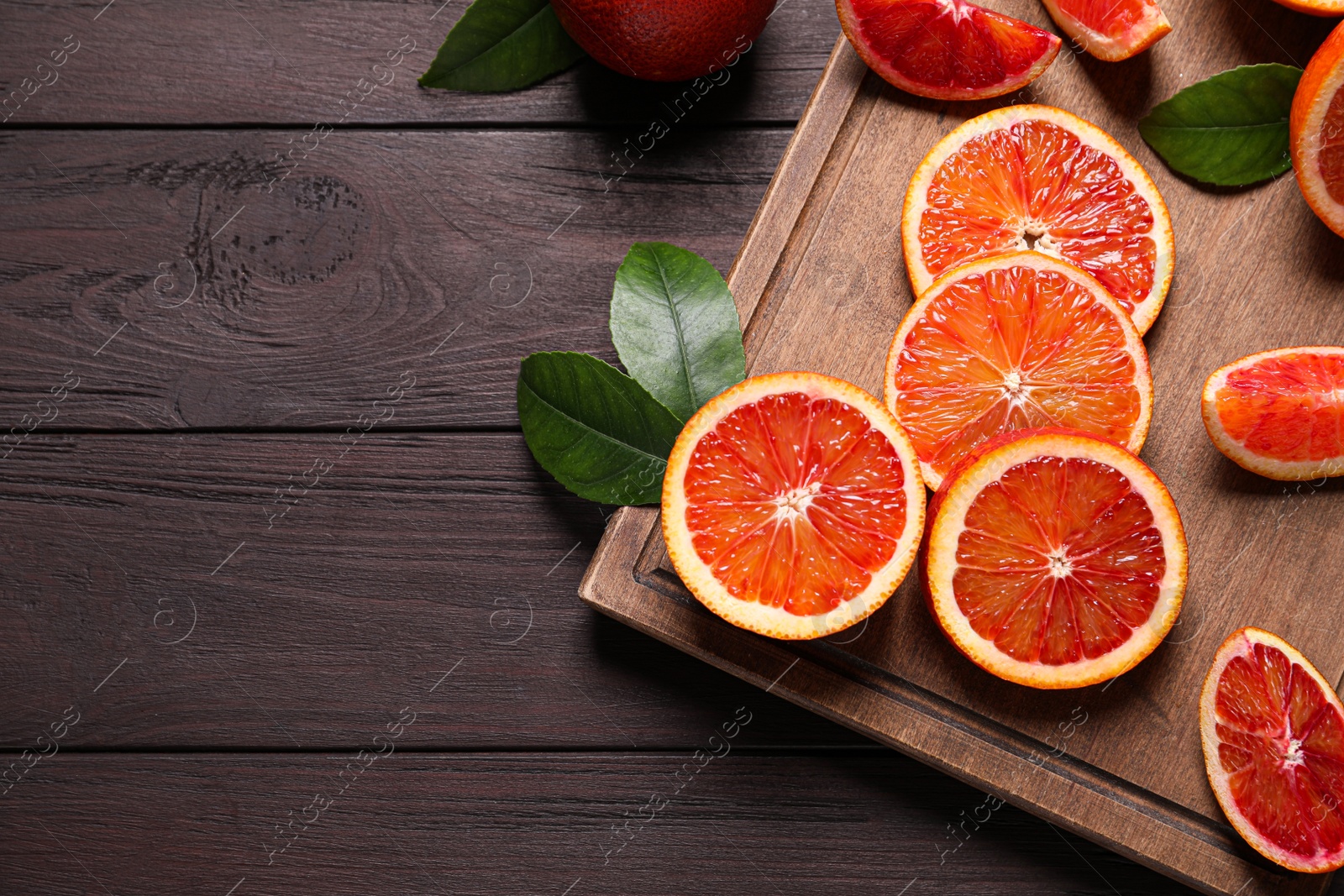 Photo of Slices of fresh ripe red oranges on wooden table, flat lay. Space for text