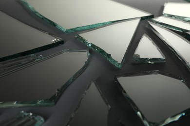 Photo of Shards of broken mirror on dark grey background, closeup