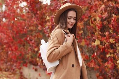 Photo of Beautiful young woman with stylish white backpack in autumn park